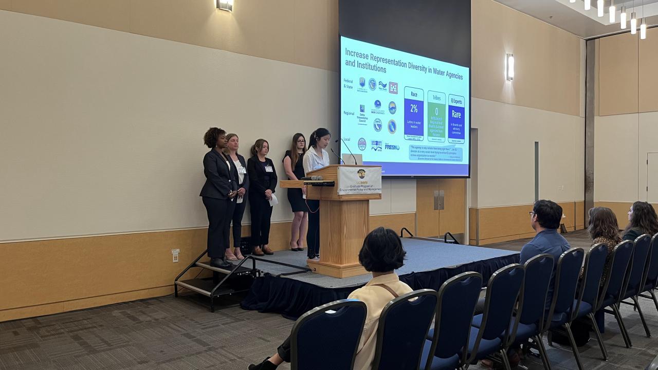 Group of EPM students at the stage doing a presentation for the Policy Symposium June 2023