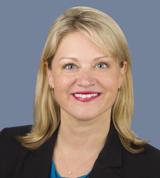 Misty Humphries in front of a grey background wearing a black blazer