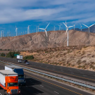 Highway with cars and trucks and hills with wind turbines
