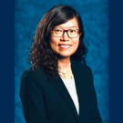 Dr. Yin Allison Liu is smiling for a close-up headshot in front of a plain blue background. She is dressed professionally, wearing glasses and a blazer. 