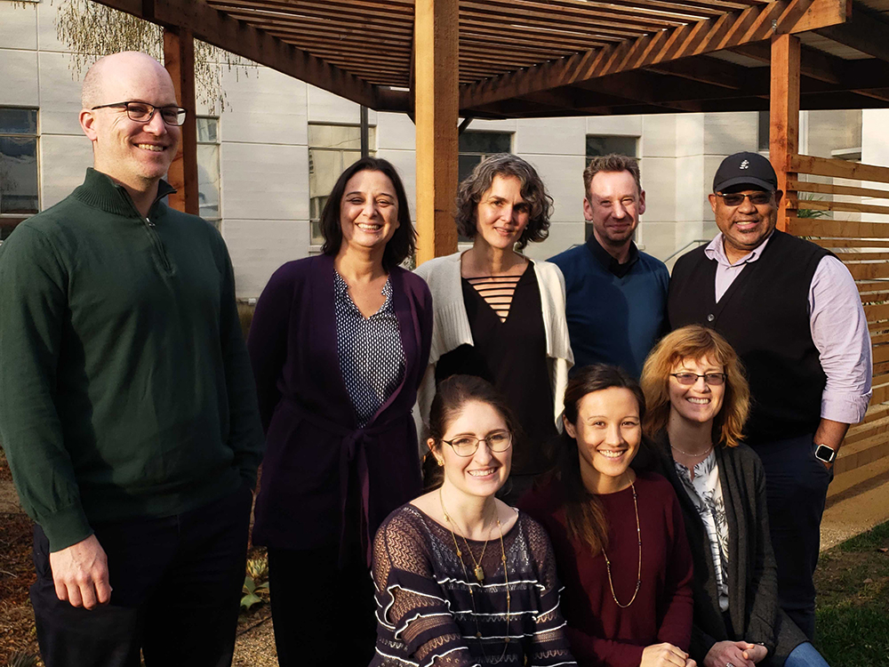 a group of adults standing outside under a pergola