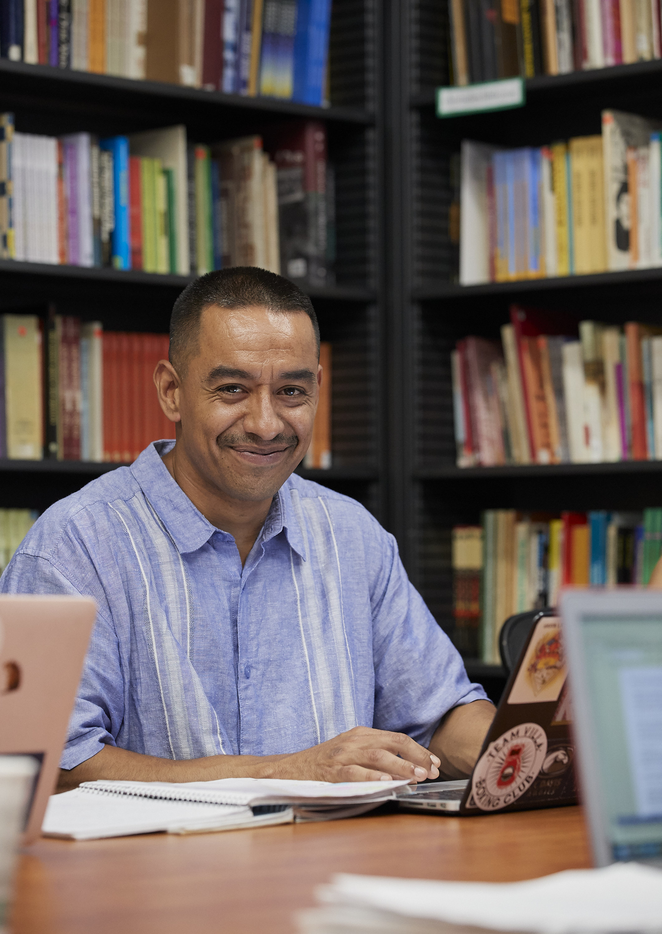 a man smiling with shelves of books behind him 