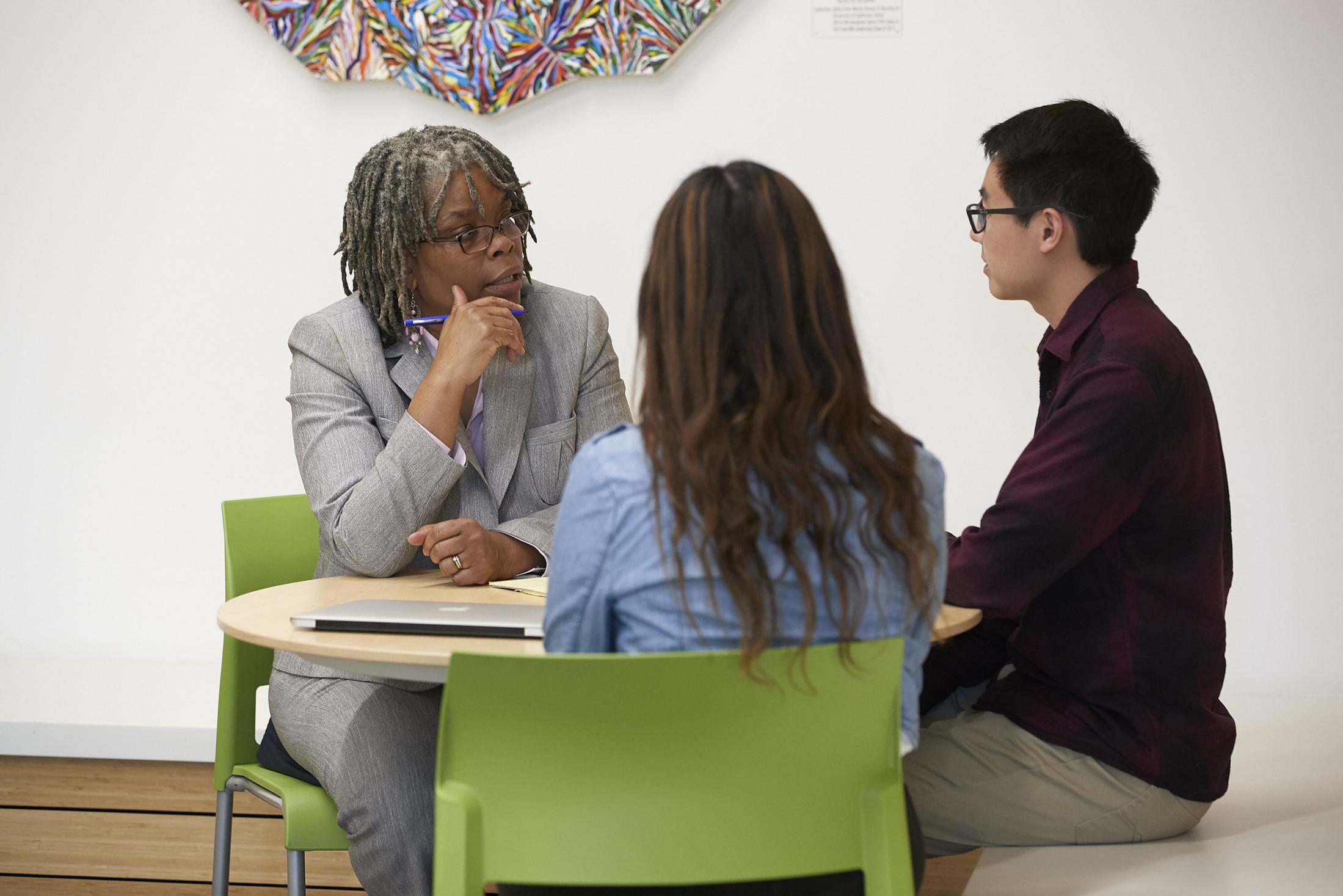 woman sitting at a table talking to two younger people