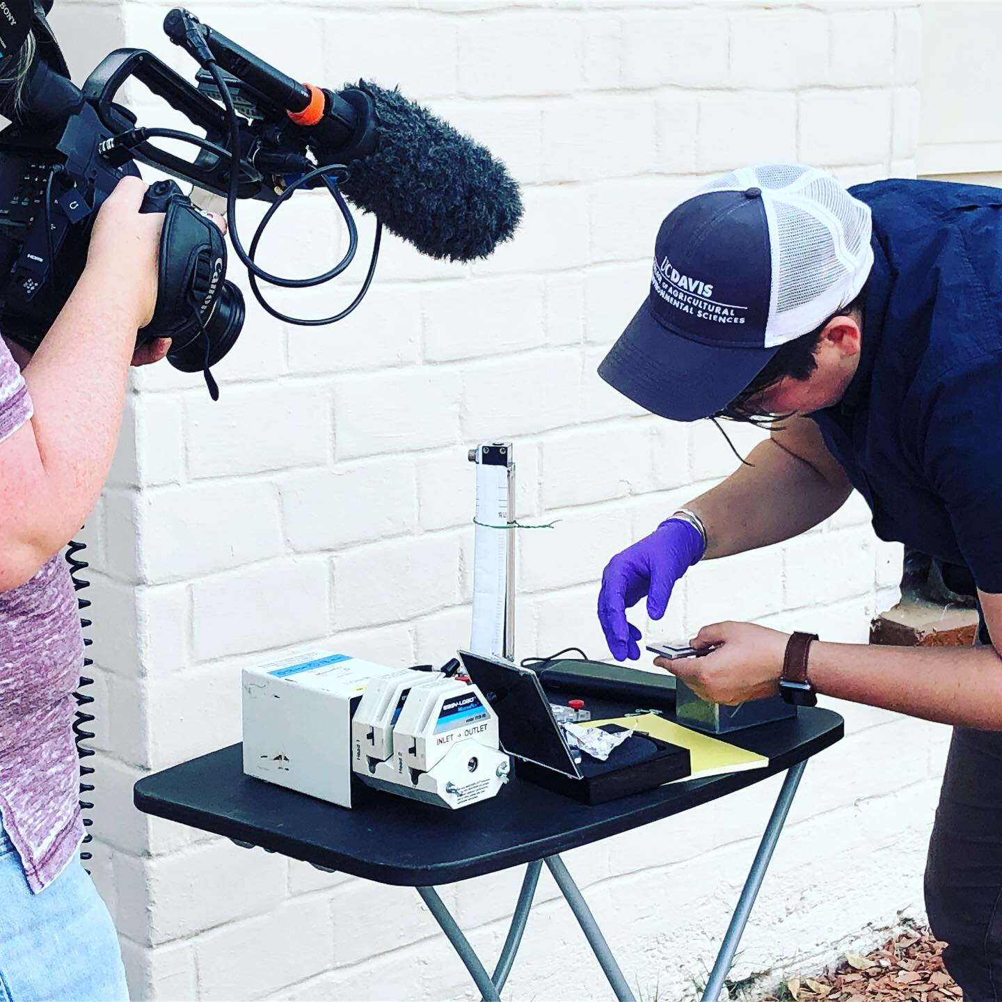 Clare Cannon does work on a small table using gloves while a video camera is pointed towards the table