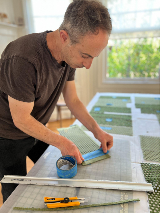 Man working at a table using tape on tactile components for a scale model 