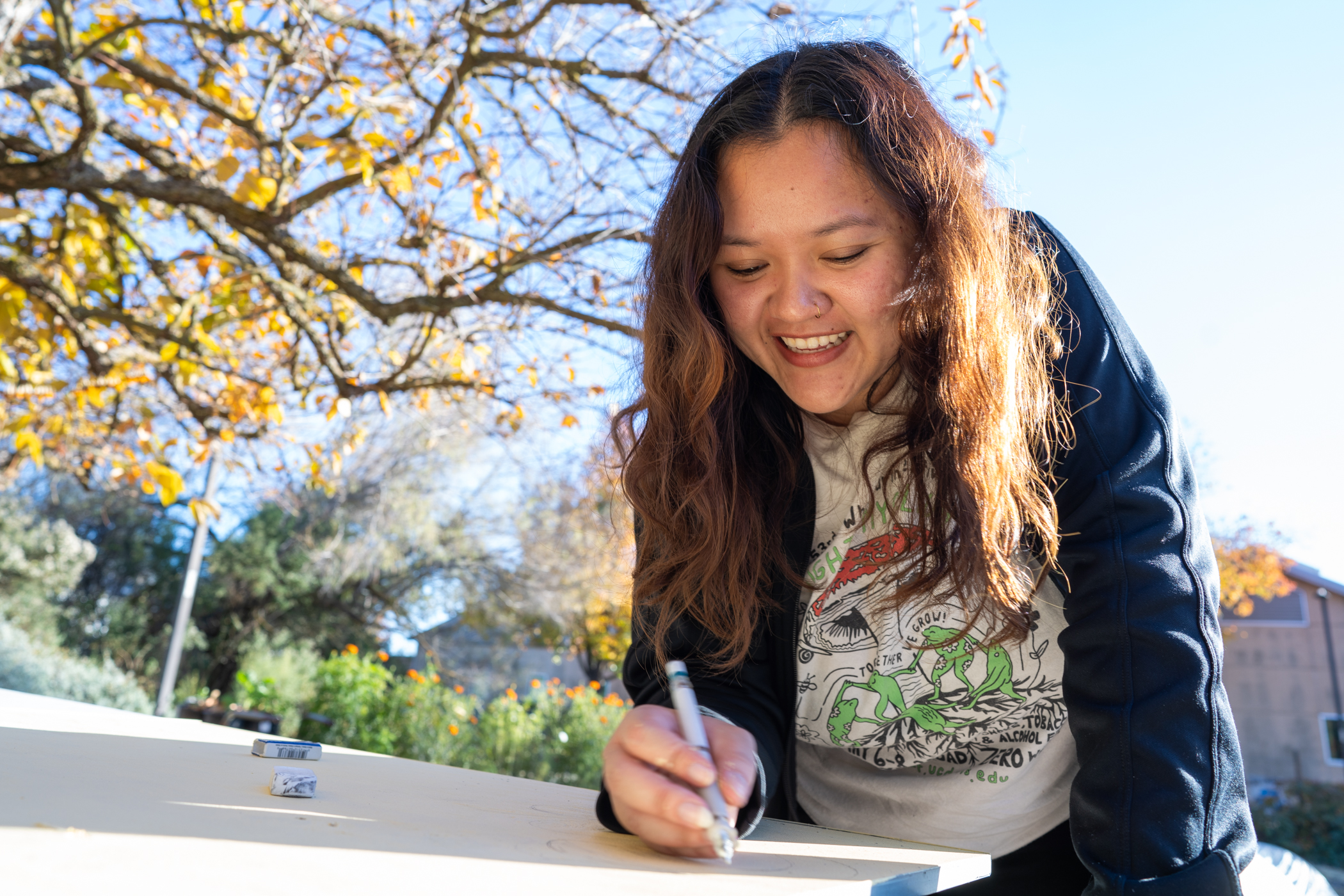 A person working outdoors holding a crayon to draw.