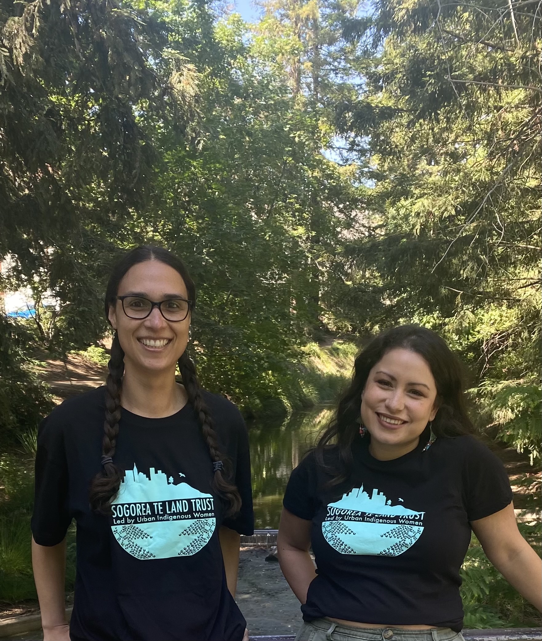 two women wearing matching shirts pose outside for a photo