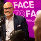 Michael Rios smiling with a mic talking to Chancellor May on the side