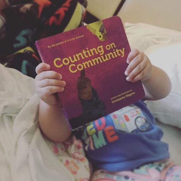 a small child holding a book in front of her face 