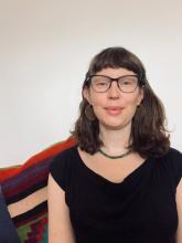Beth Ferguson smiling wearing a green necklace and black shirt and eyeglasses