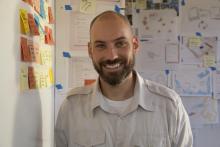 Thomas Maiorana smiling in a classroom with papers on the wall