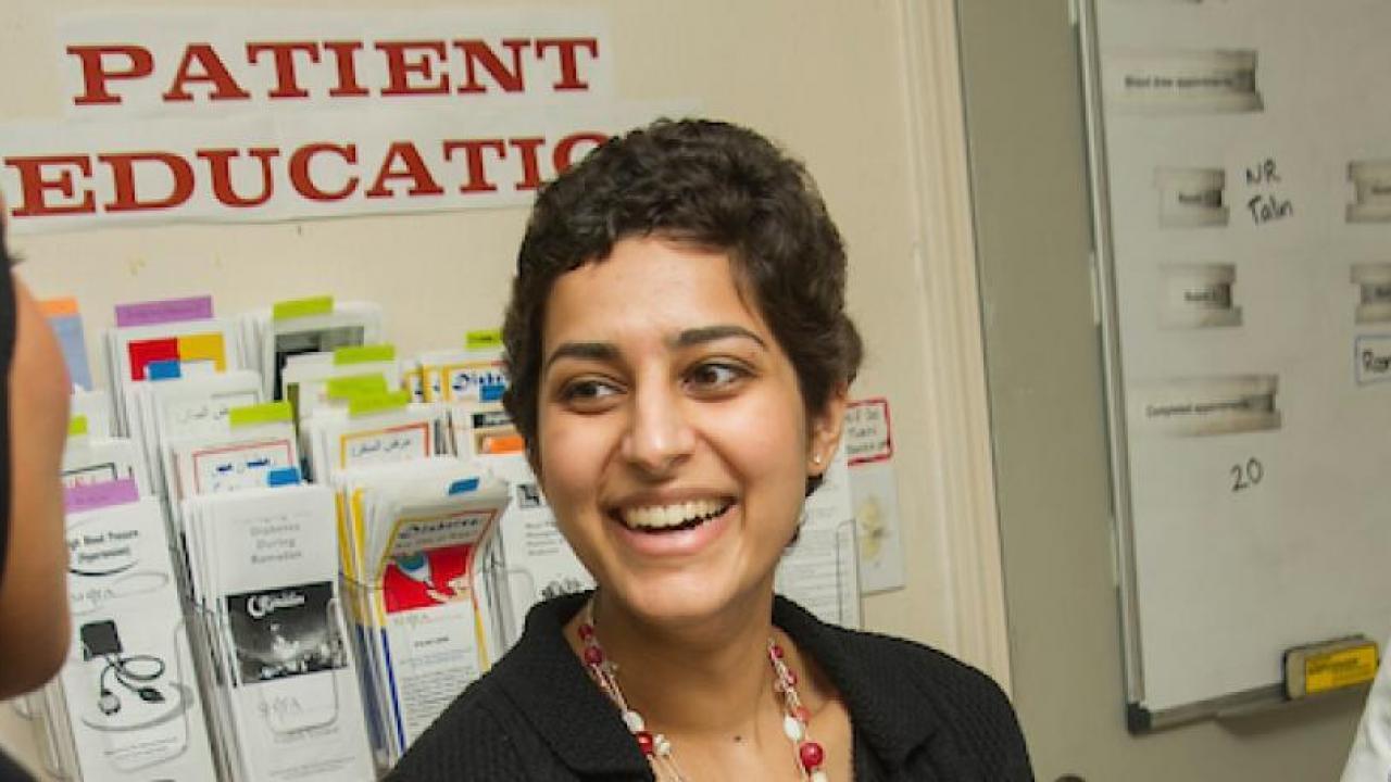 a woman with short brown hair in front of a wall that says patient education