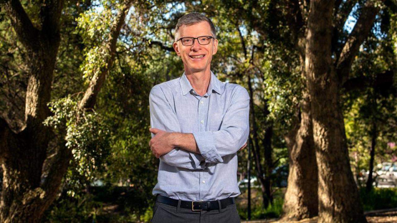 a man in a blue long sleeved shirt standing in a wooded area