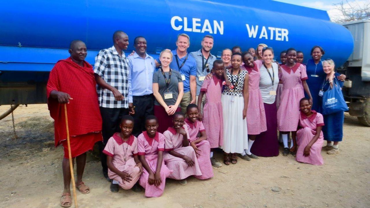 With HEART medical team and staff, Oldonyonyioke village school faculty, elders and Maasai schoolgirls, in Kenya 2018. Courtesy of Laura Van Auker/UC Davis Group of people standing in front of a large truck that reads "clean water"