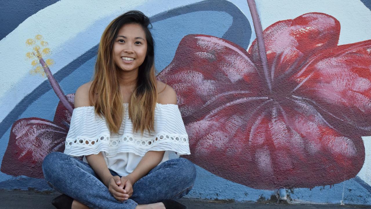 girl sitting against wall with art