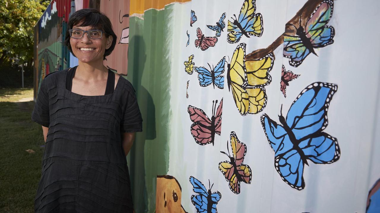 woman standing next to a butterfly mural