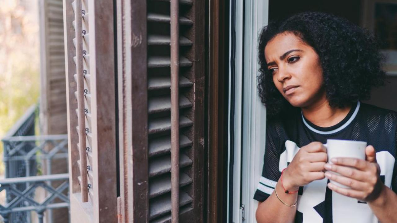 A UC Davis study suggests that COVID-19 isolation has severely affected people’s everyday lives. (Getty Images) woman holding a cup of coffee looking out a window, melancholy