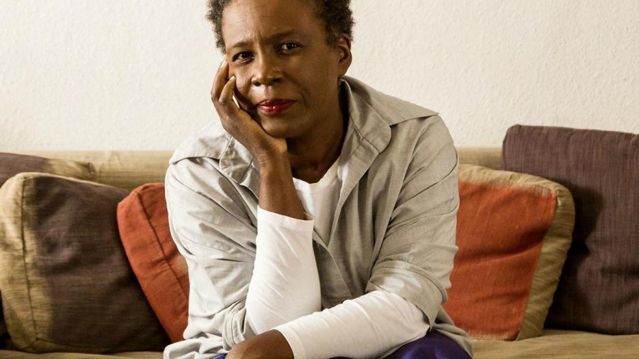 African America woman sitting on a couch looking into the camera with her head in her hand