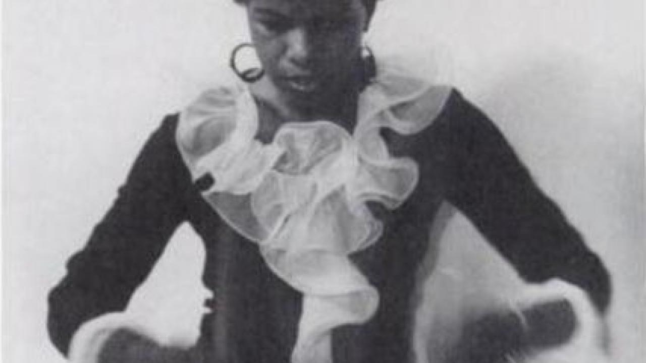 an African American woman in a black dress with a big white ruffle 