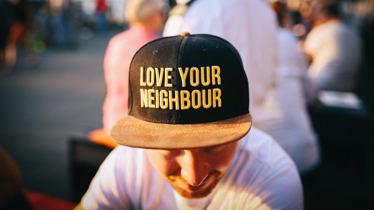 man wearing a hat that says "love your neighbor"