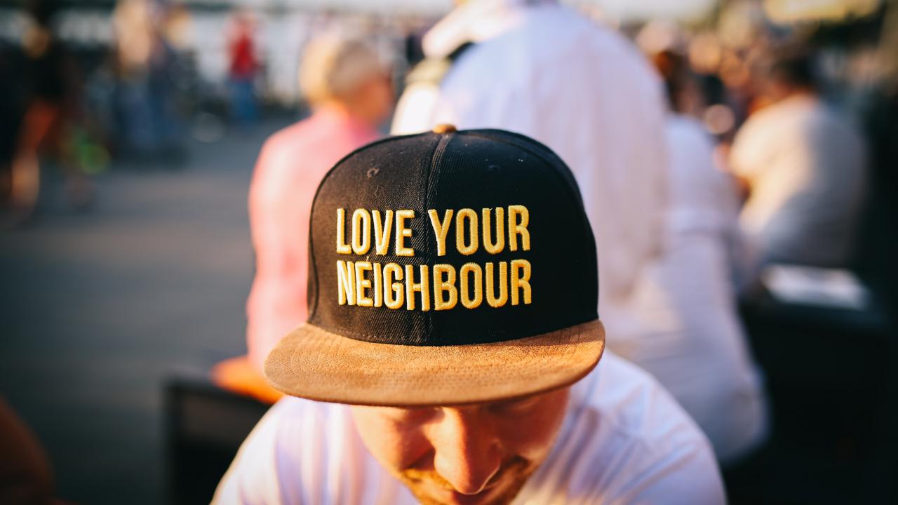 man wearing a hat that says "love your neighbor"
