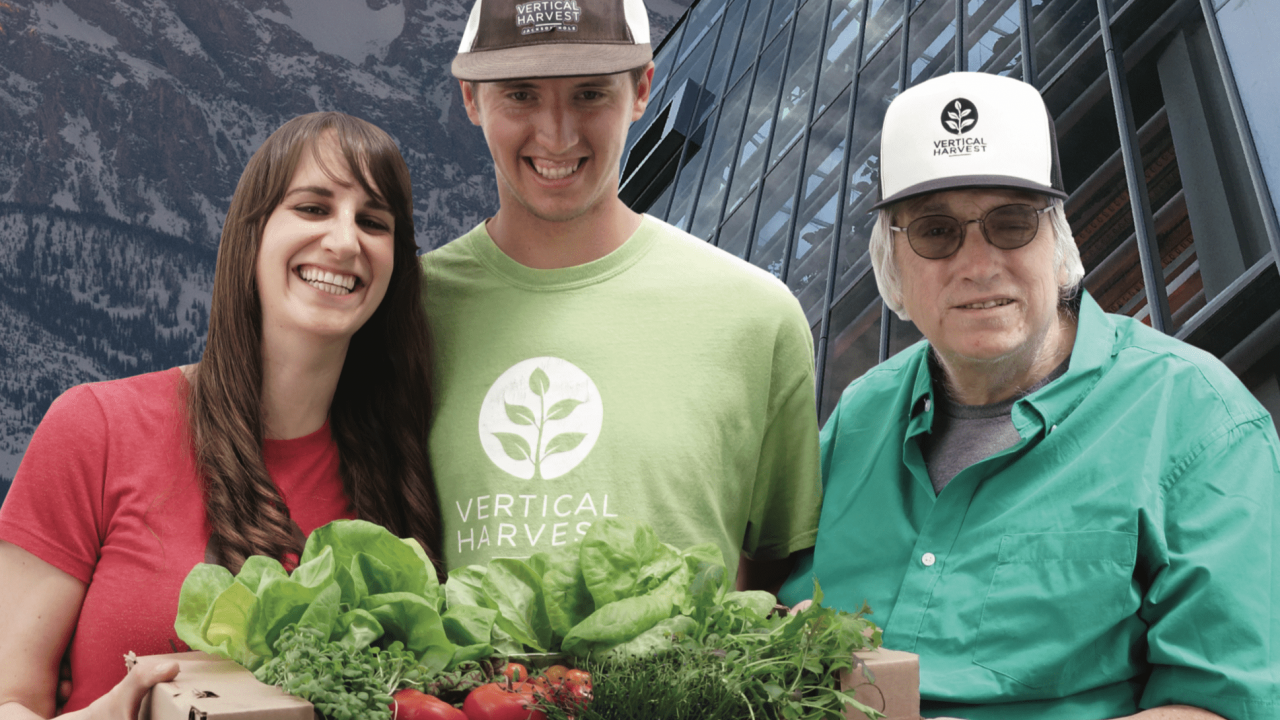 group of three individuals with produce in front of a cityscape
