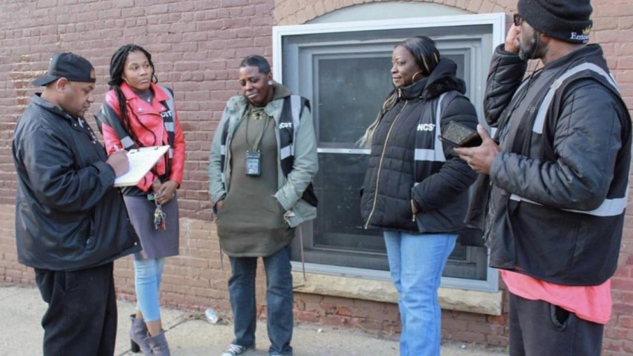 group of people standing in front of a brick wall