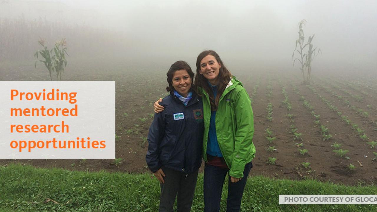 Two women standing in a misty field, text reads "providing mentored research opportunities"