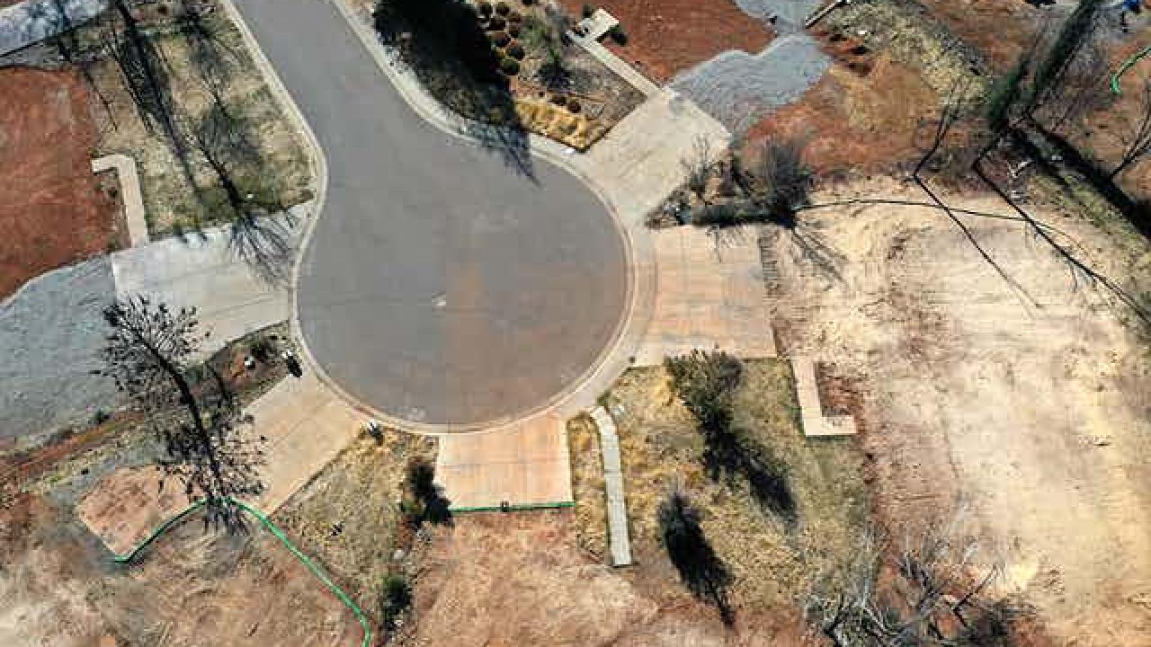 Former home lots are evident in a cul-de-sac where all that remains is the driveways and sidewalks to where homes once stood. The lots, where the homes burned, have been razed.