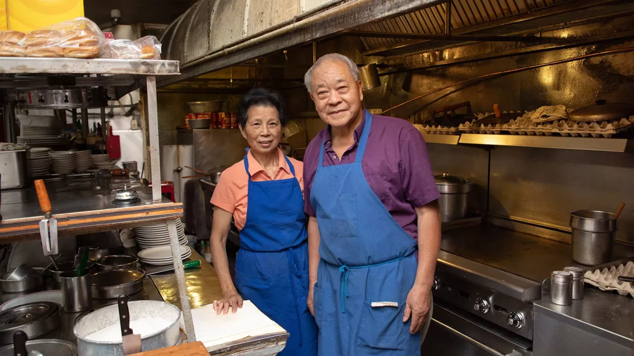 Two people stand in an old kitchen