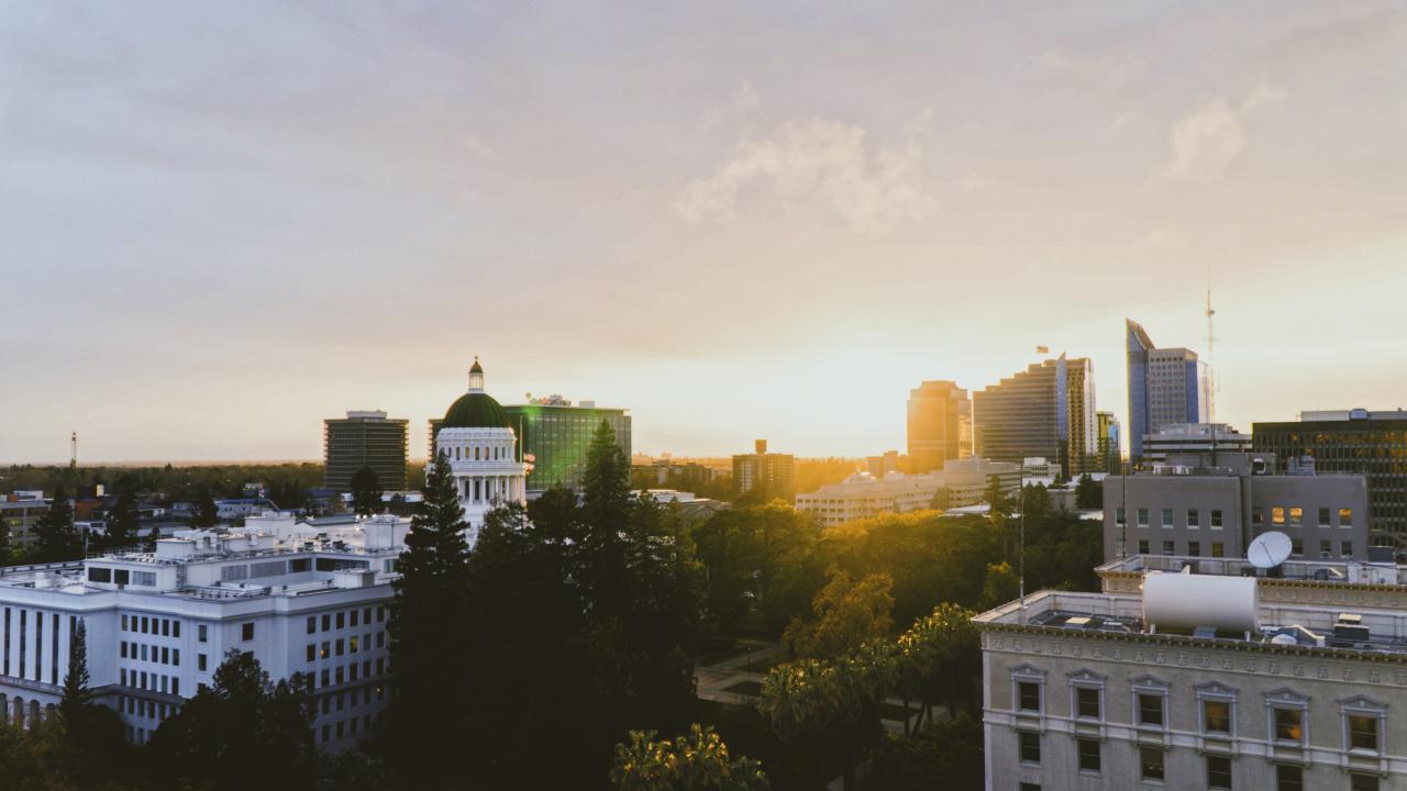 A photograph of Downtown Sacramento and the State Capitol with the sun setting in the background.