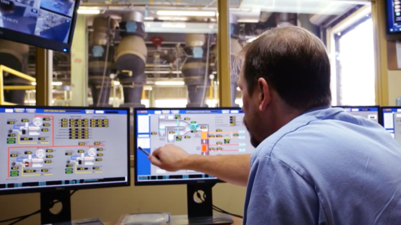 Image of plant operator at the central heating and cooling plant pointing at a computer monitor.
