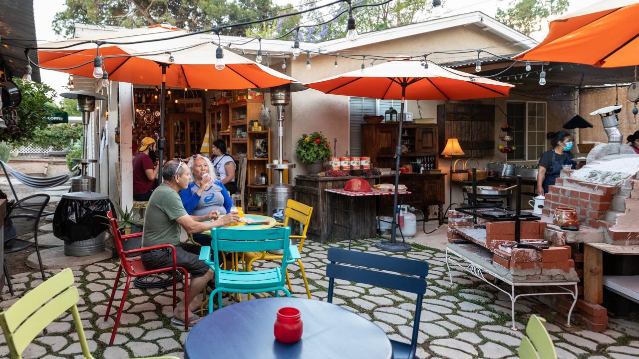 a patio backyard with umbrellas and a couple eating dinner