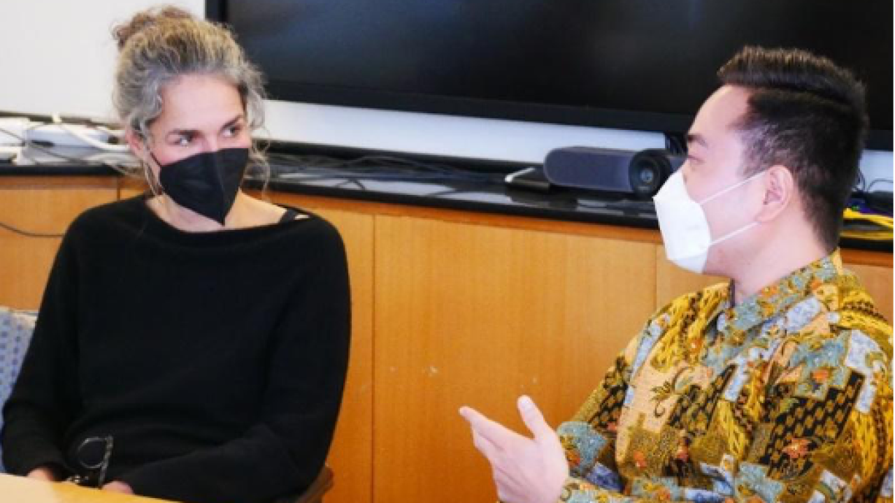 woman in a mask talking to a student inside a classroom