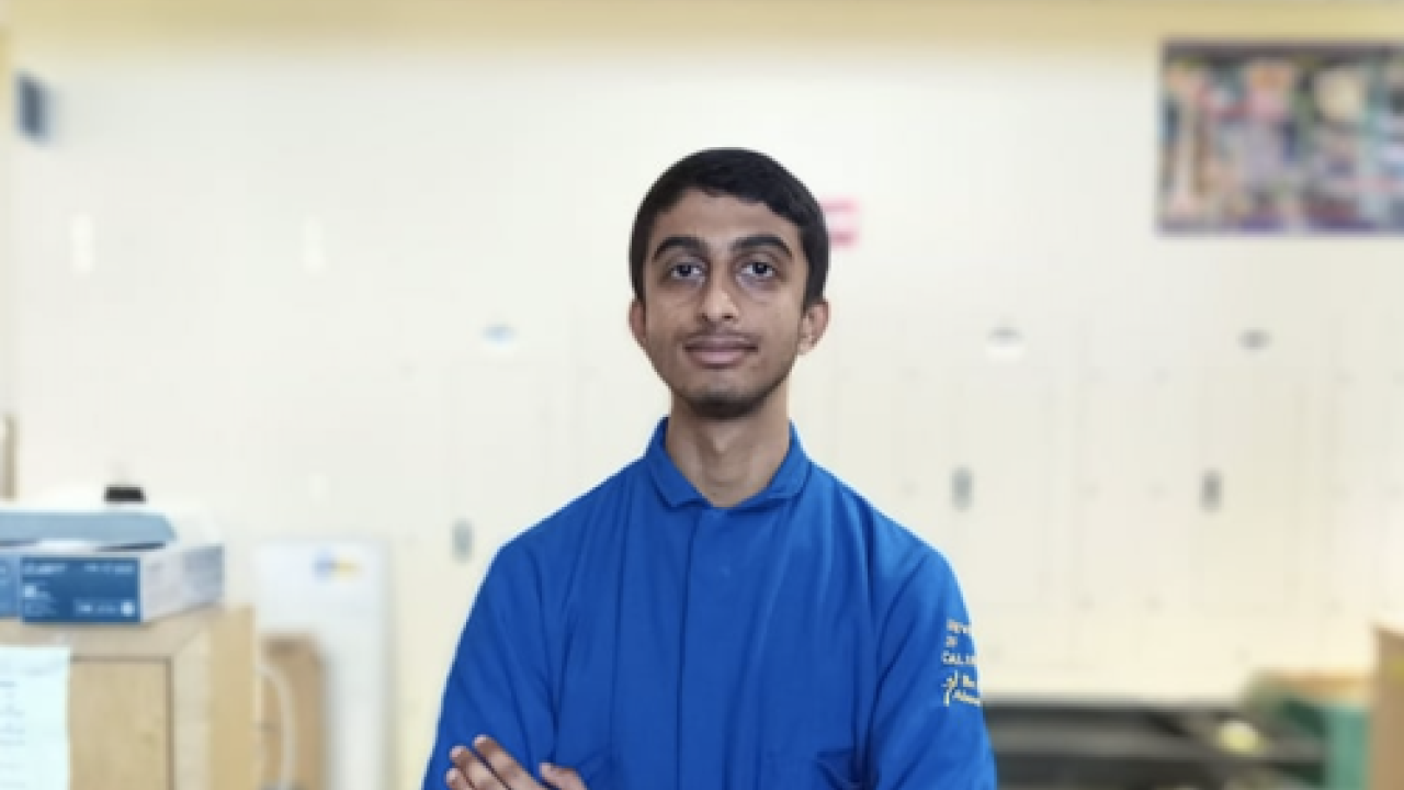 Young man in a blue lab coat inside a laboratory