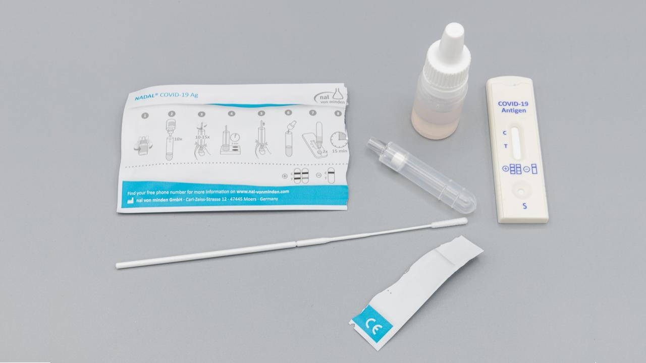 COVID-19 Antigen test kit laid out in front of a grey background