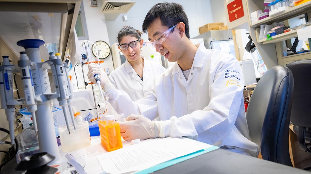 Biomedical Engineering graduate students Leora Goldbloom-Helzner and David Wang in a laboratory with PPE on handling samples and lab equipment