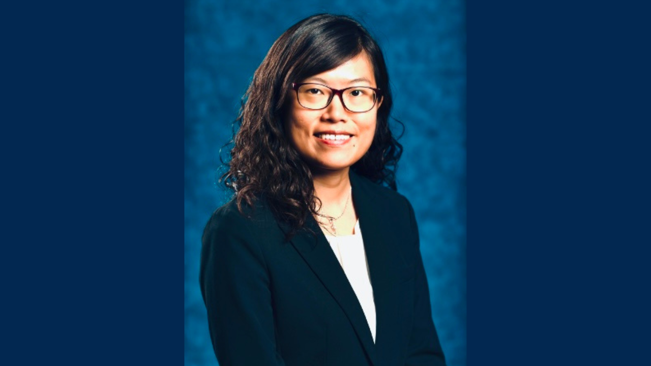 Dr. Yin Allison Liu is smiling for a close-up headshot in front of a plain blue background. She is dressed professionally, wearing glasses and a blazer.