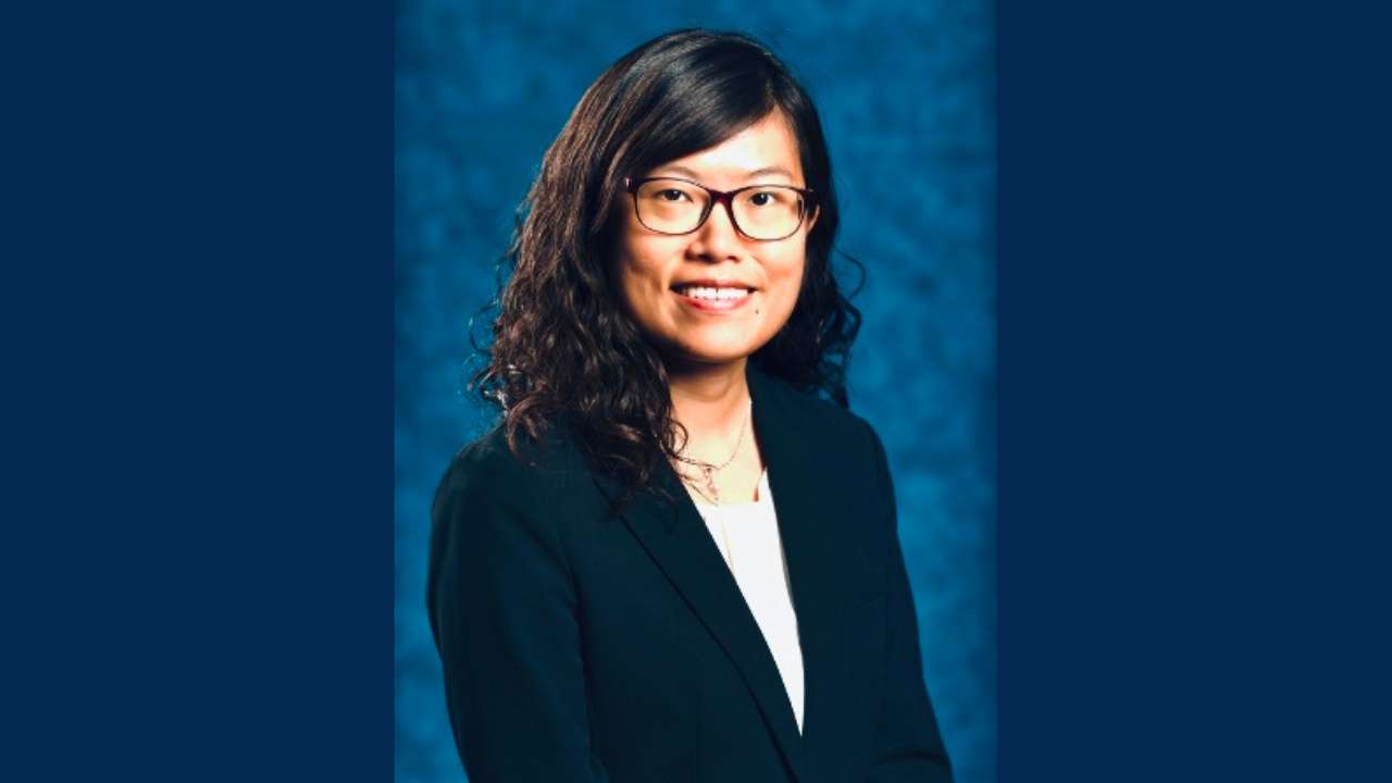 Dr. Yin Allison Liu is smiling for a close-up headshot in front of a plain blue background. She is dressed professionally, wearing glasses and a blazer. 