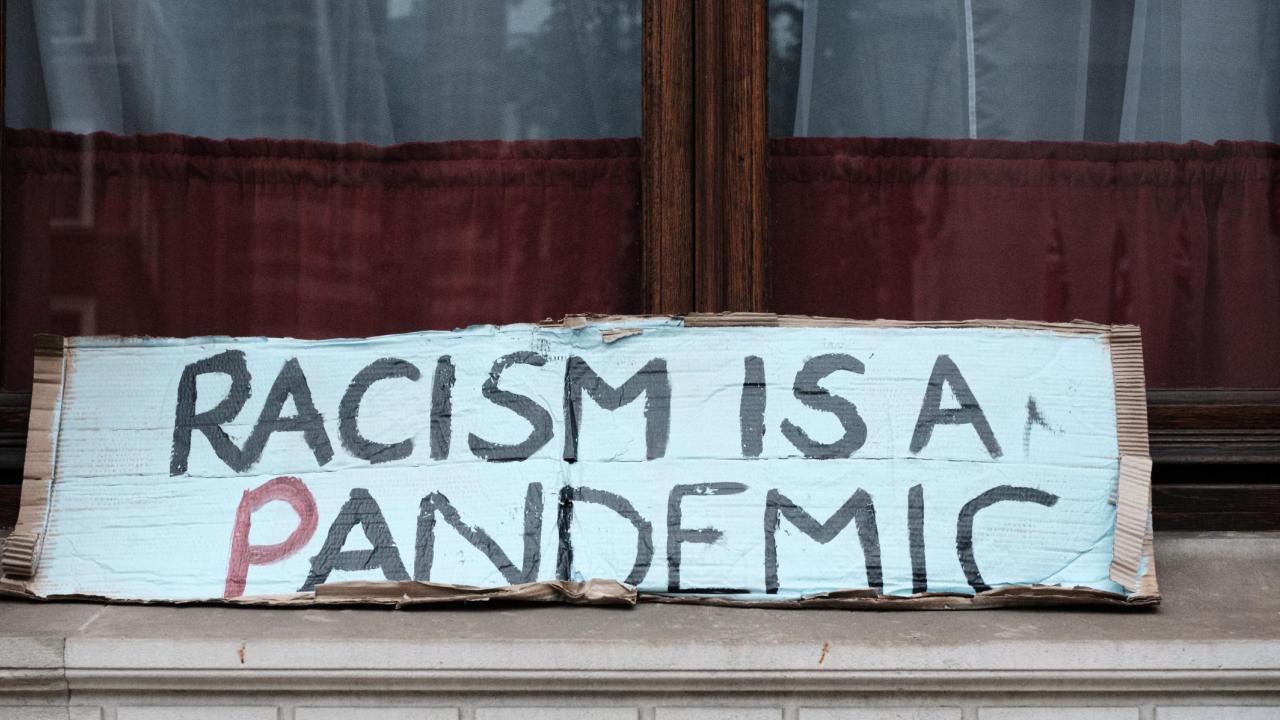 a sign that reads "racism is a pandemic"