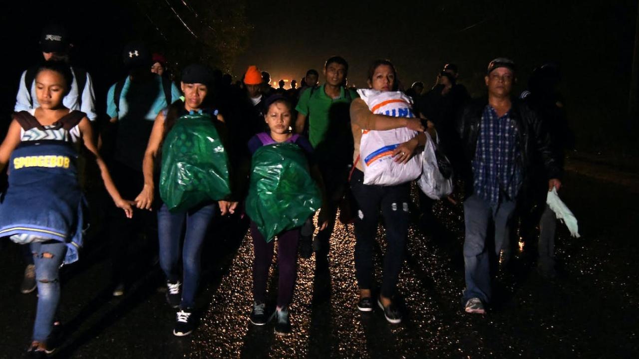 Group of Honduran migrants walking together as a group, carrying their backpacks