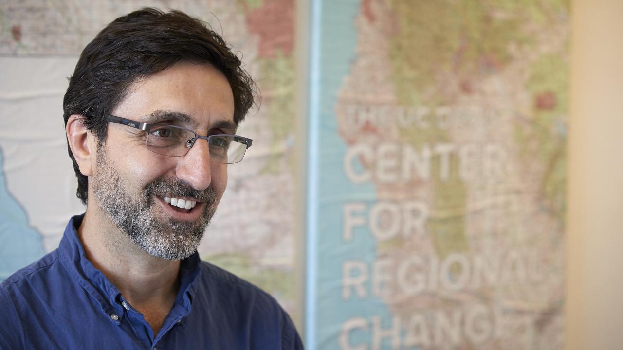 a man wearing glasses sitting in front of a map that has the words Center for Regional Change