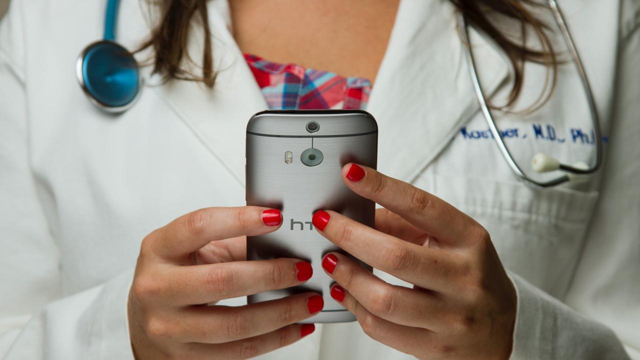 a woman in a white doctors coat holding a cell phone