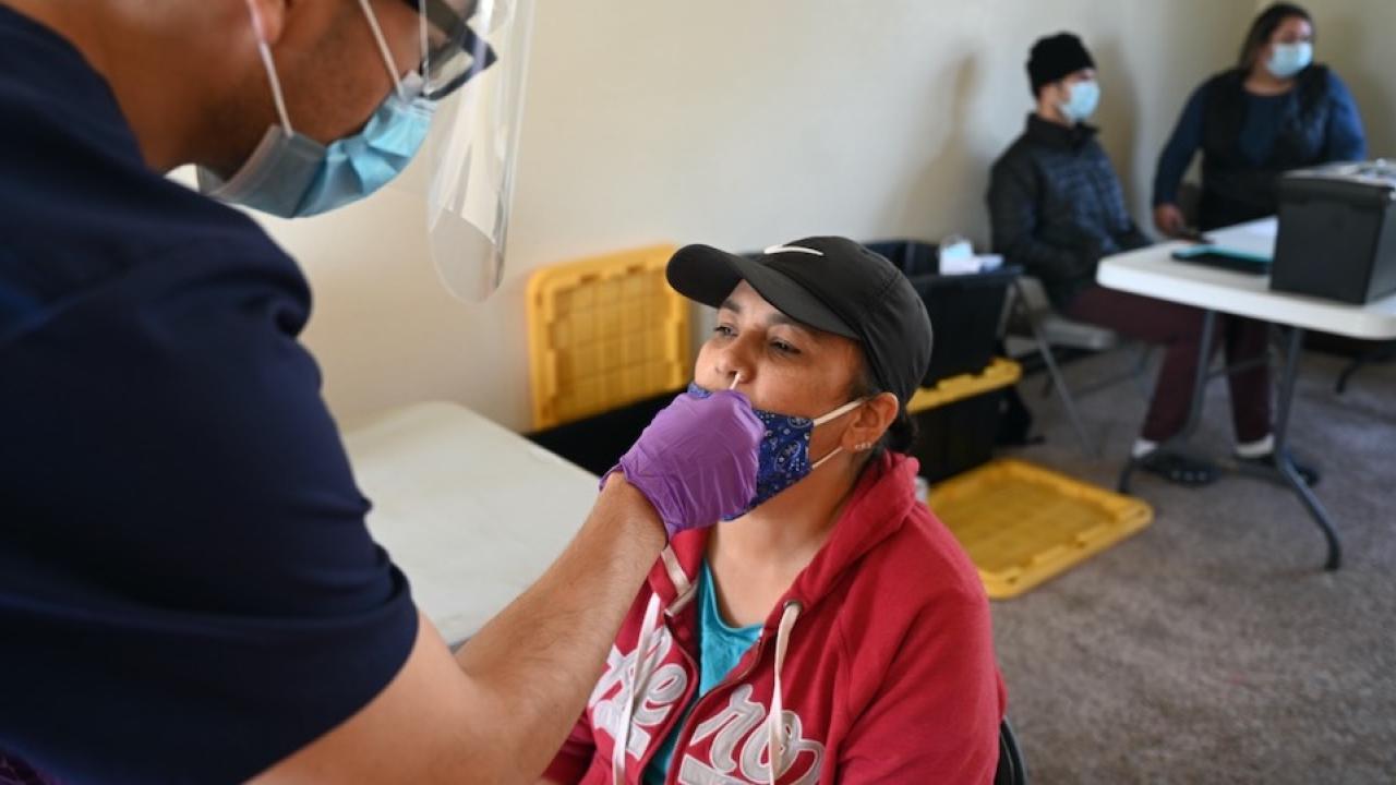 A long nasal swab is used on an individual to get tested for COVID-19 inside a building.