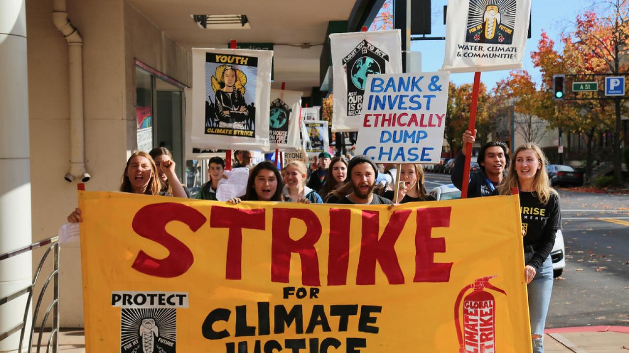a group of young people holding a yellow sign that reads "strike for climate justice"