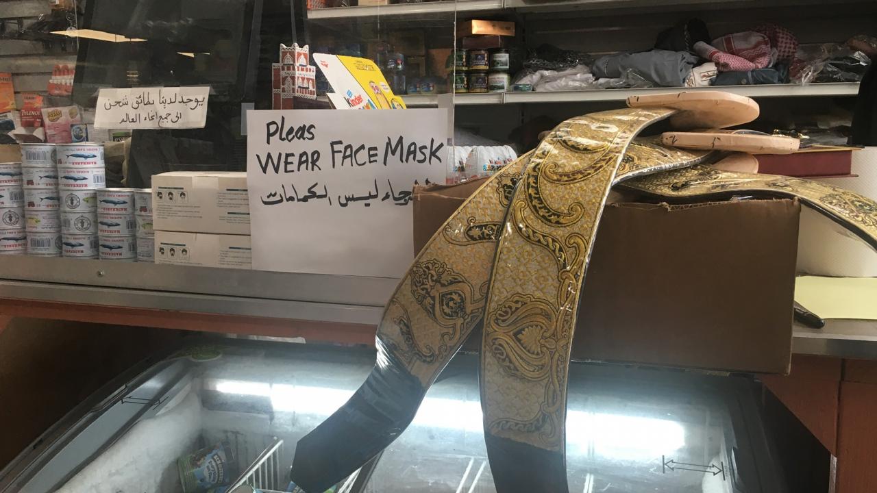a countertop in a small market with a sign that says "please wear a mask"