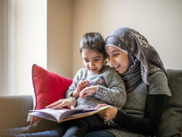 Woman holding a child and they are reading a book together