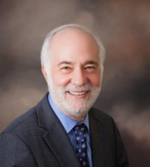 Man smiling in a suit in front of a gray background