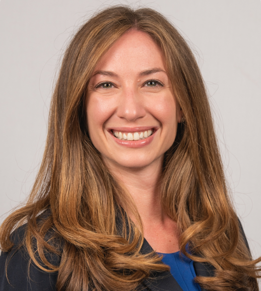 Close up headshot of a woman smiling in front of a plain background