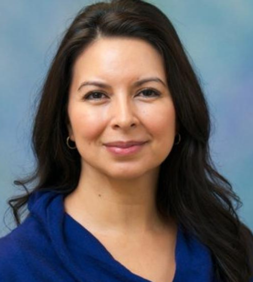 Close up headshot of a woman smiling in front of a plain background